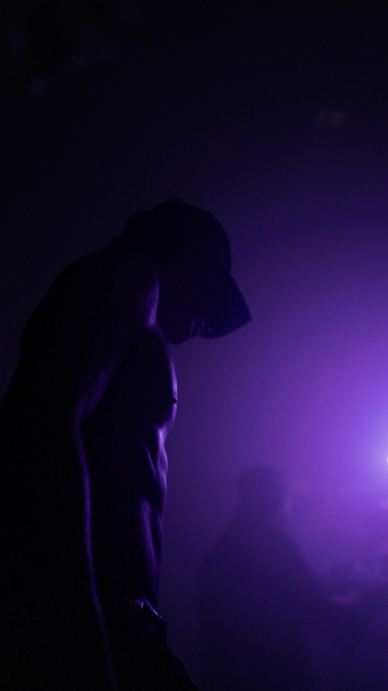 Figure in purple haze, head bowed