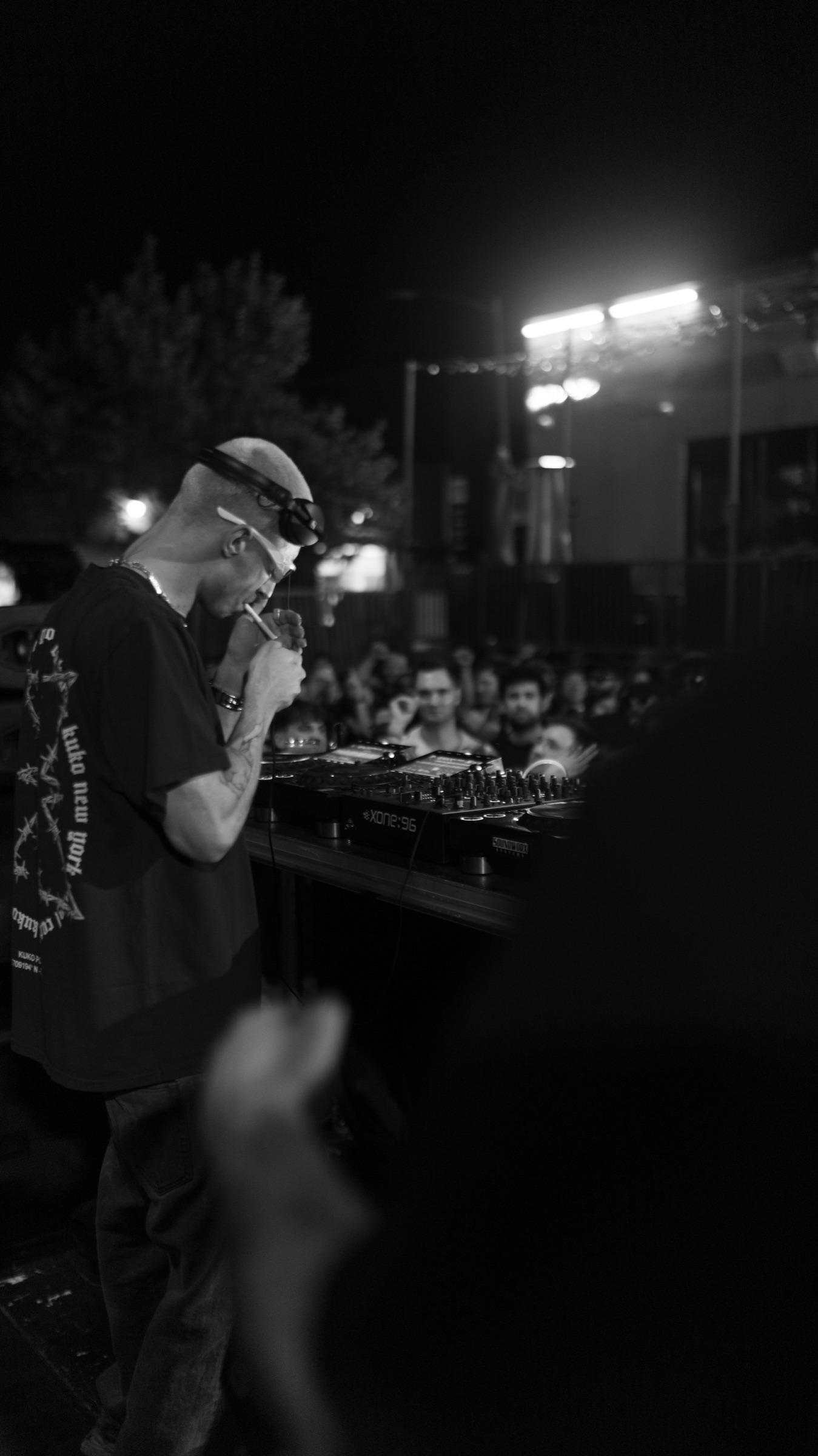 DJ in sunglasses at the booth under floodlights, night