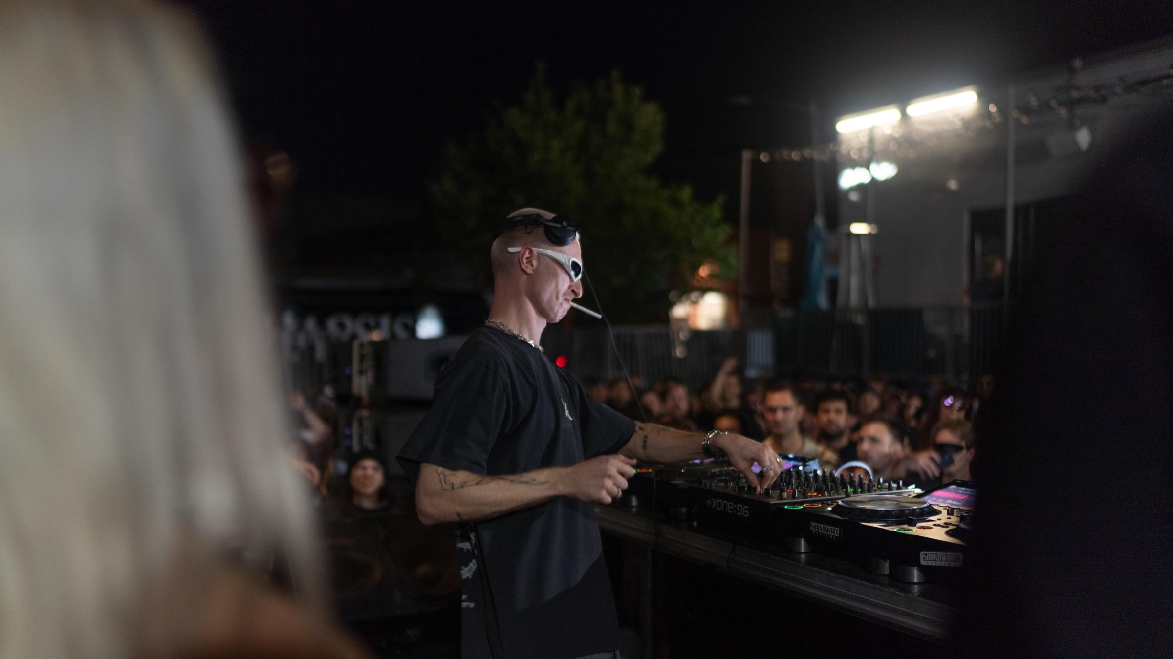 DJ behind the decks, seen past a dancer in the foreground