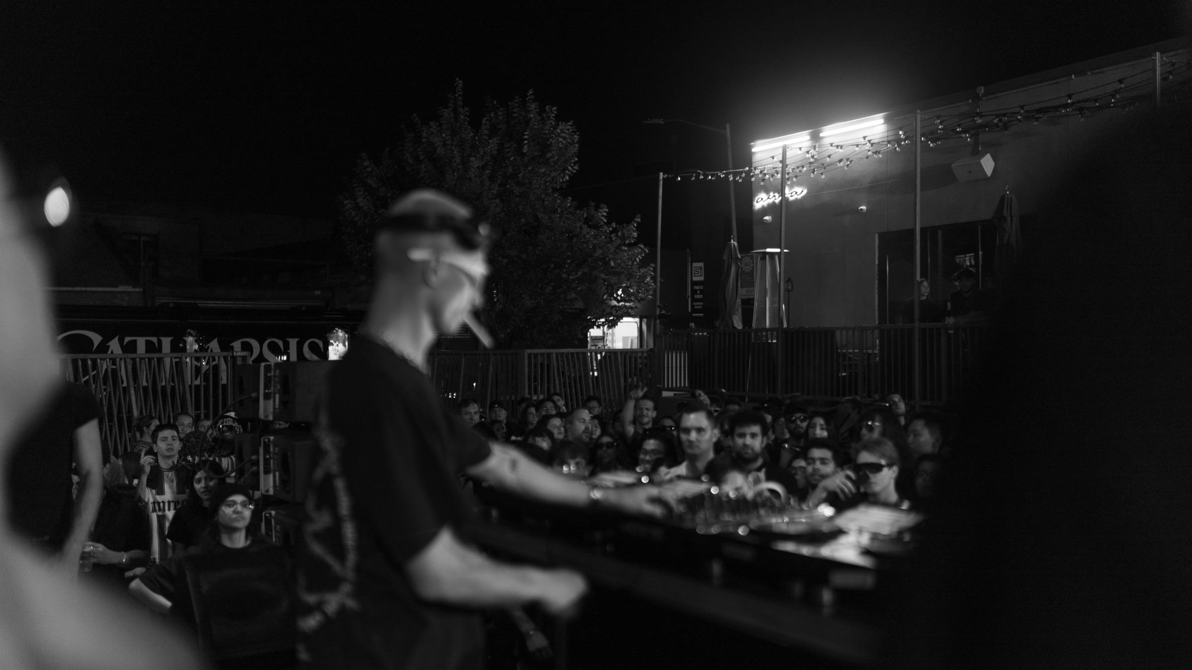 DJ at the booth with the crowd and floodlights beyond