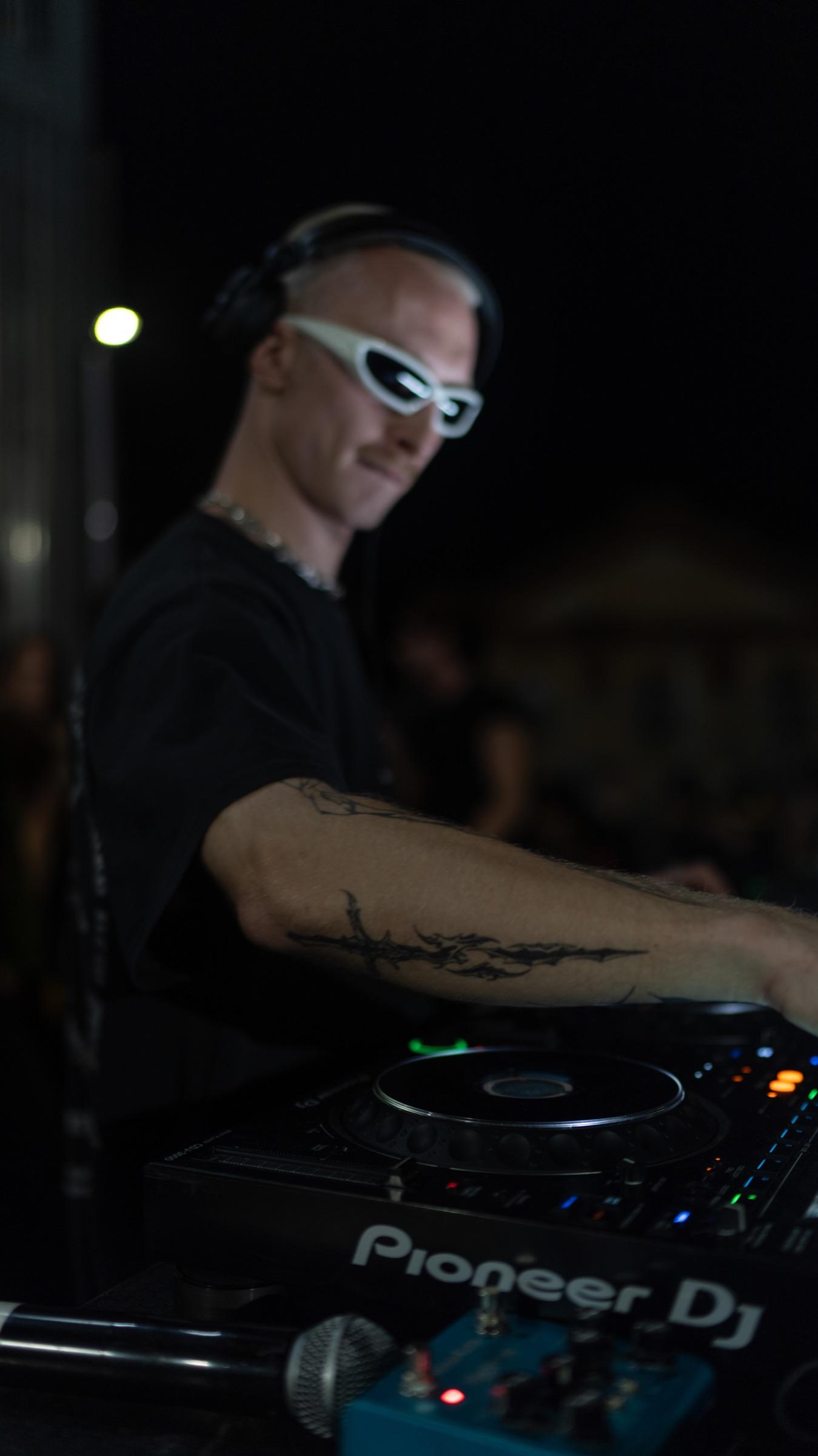 Close-up of a DJ in white sunglasses mixing on Pioneer decks