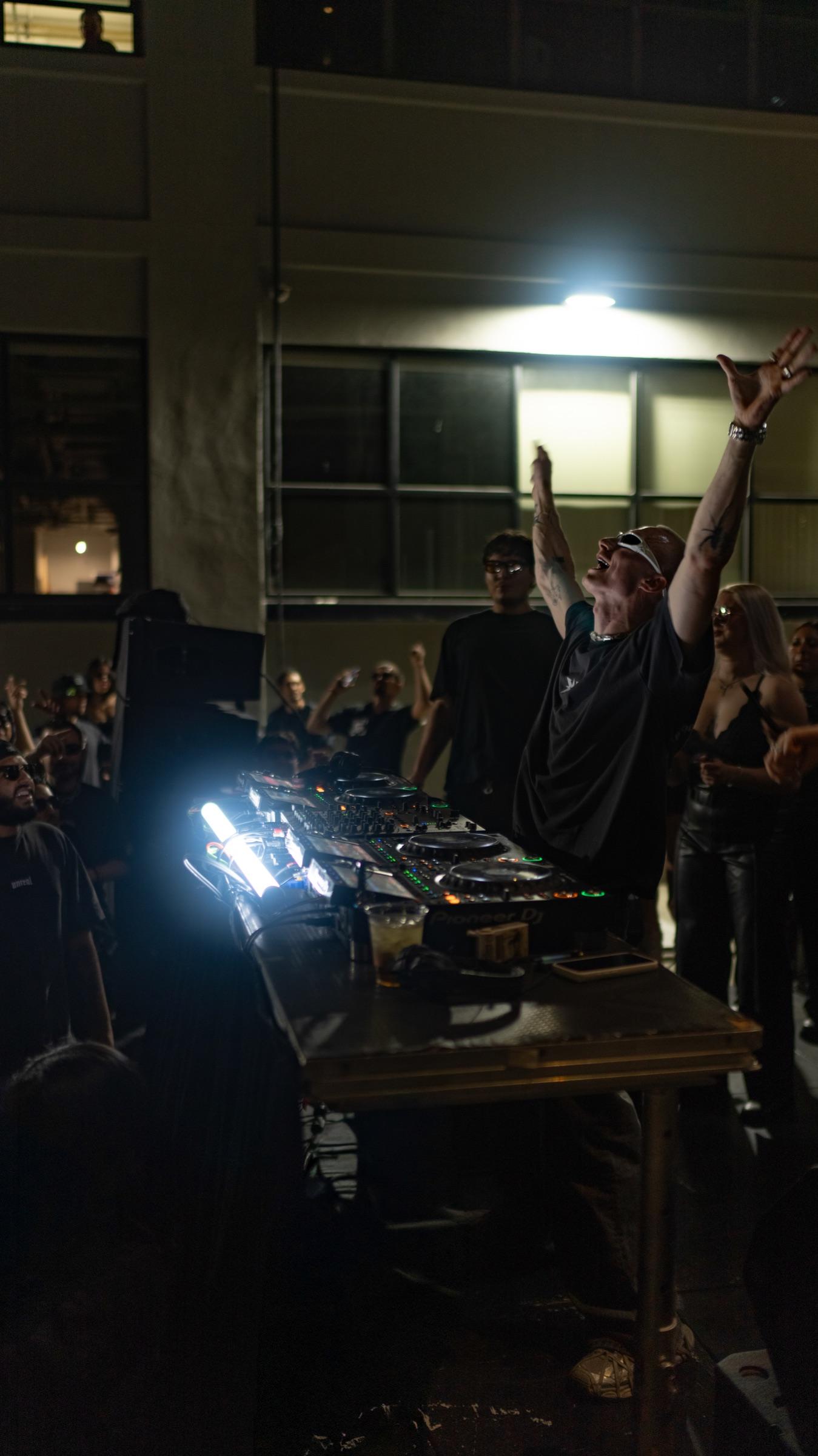 DJ under a wall lamp with one arm raised