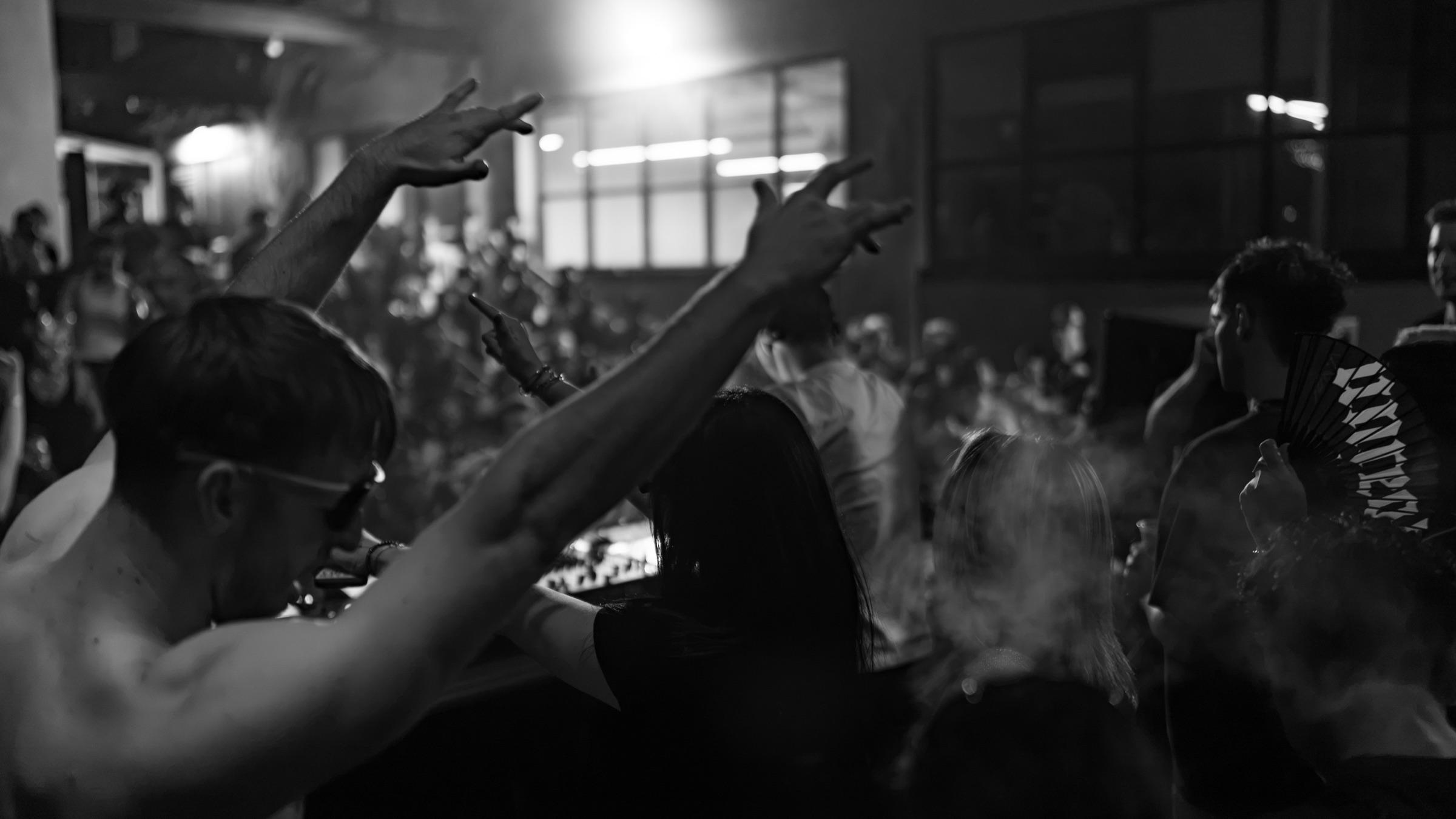 Black-and-white: hands raised through smoke