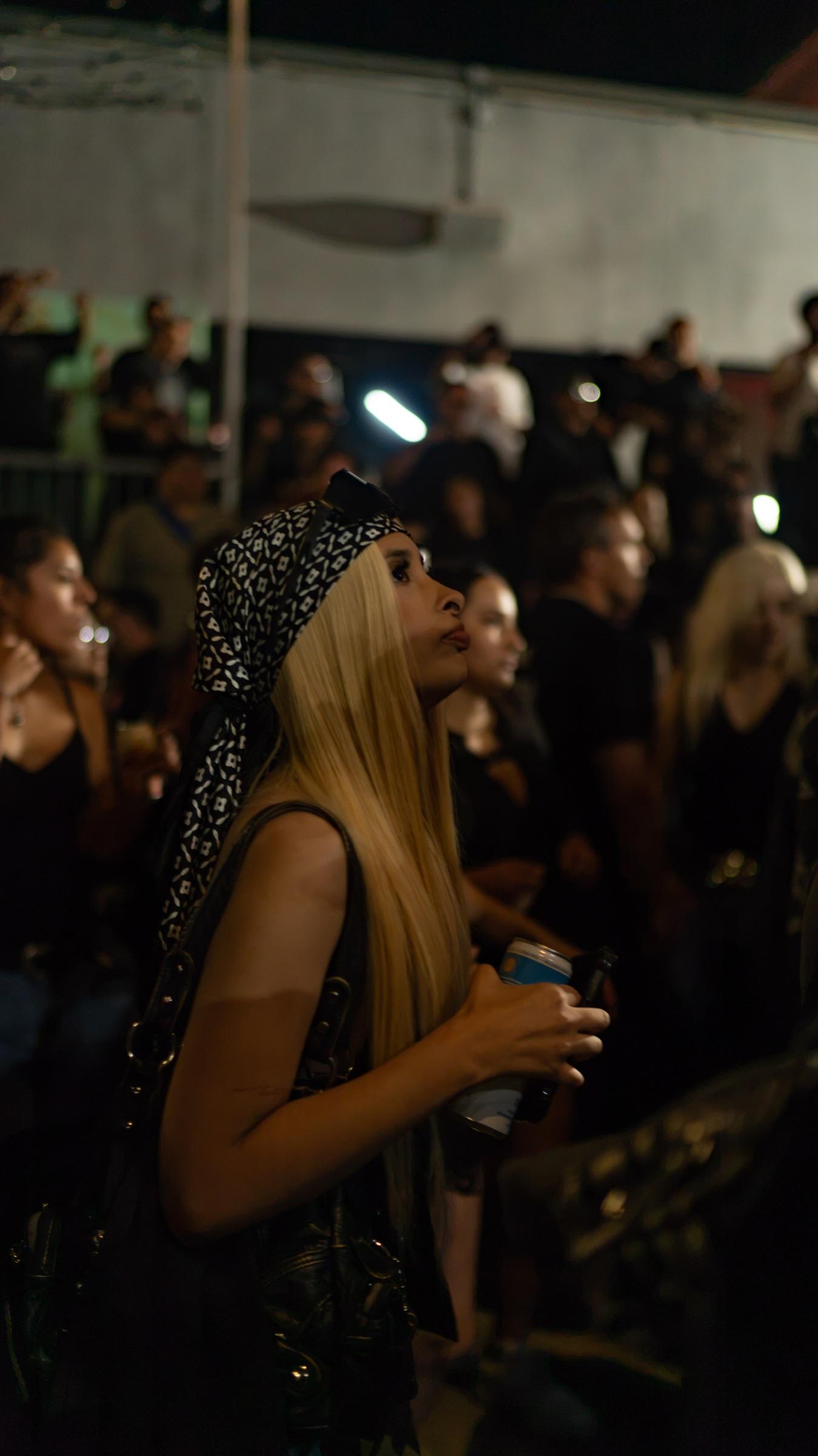 Dancers in the crowd, one in sunglasses with a drink