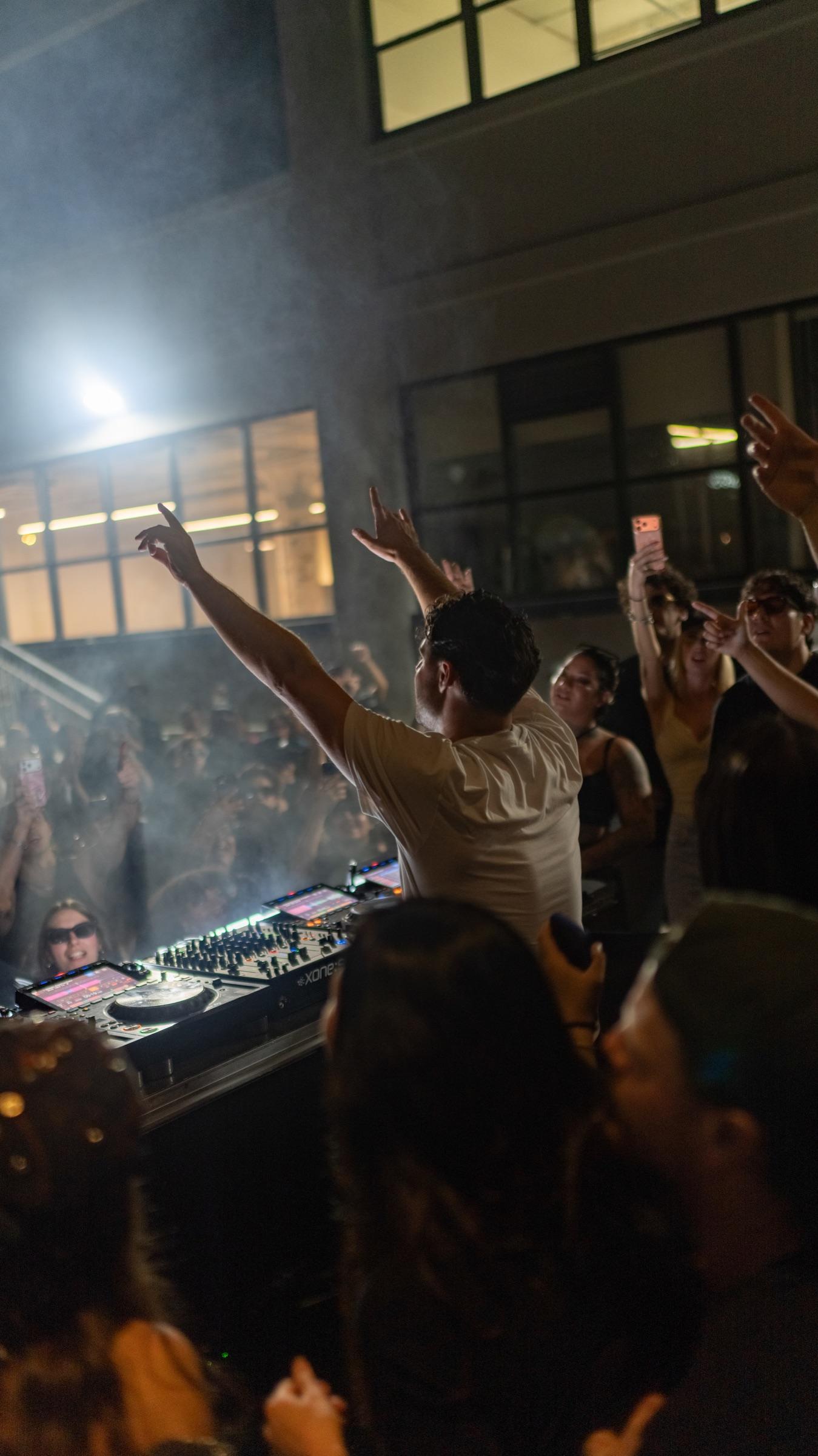 Dancer with arms up in smoke beside the booth