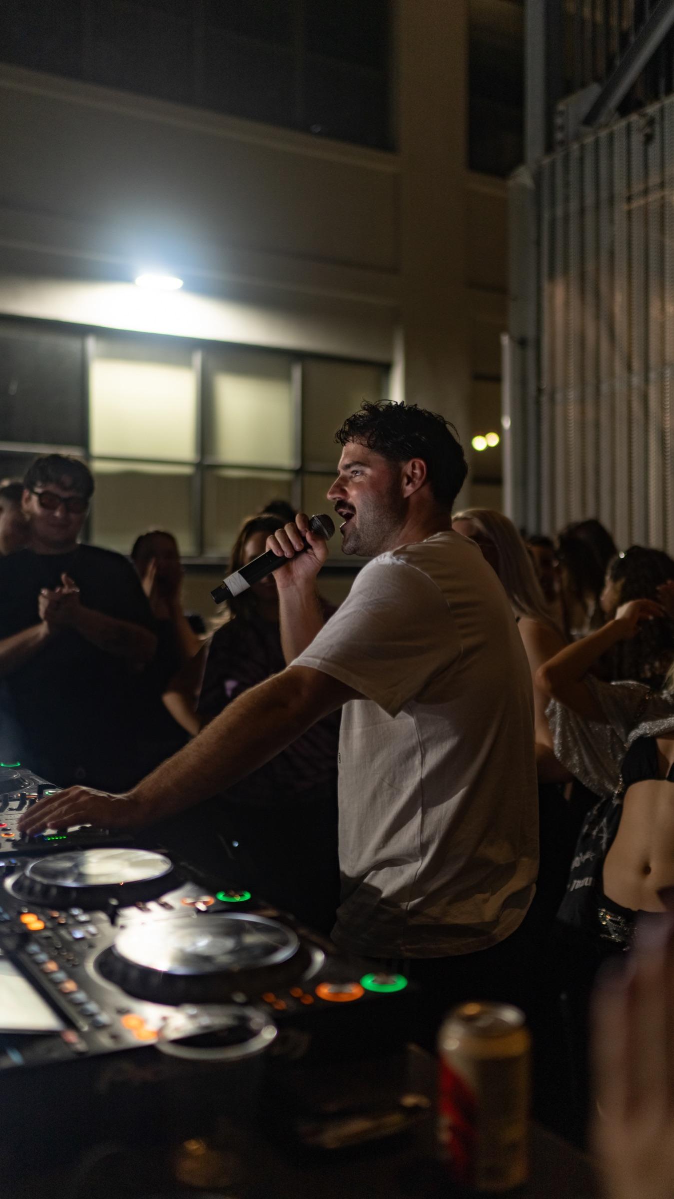 DJ speaking into a microphone at the booth
