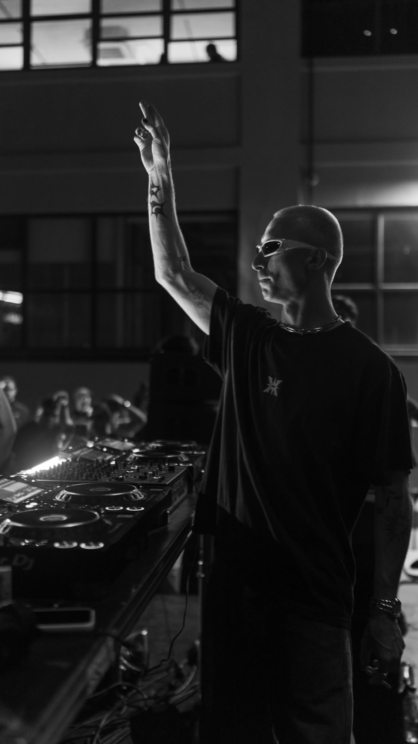 Black-and-white: DJ with an arm raised, vertical frame