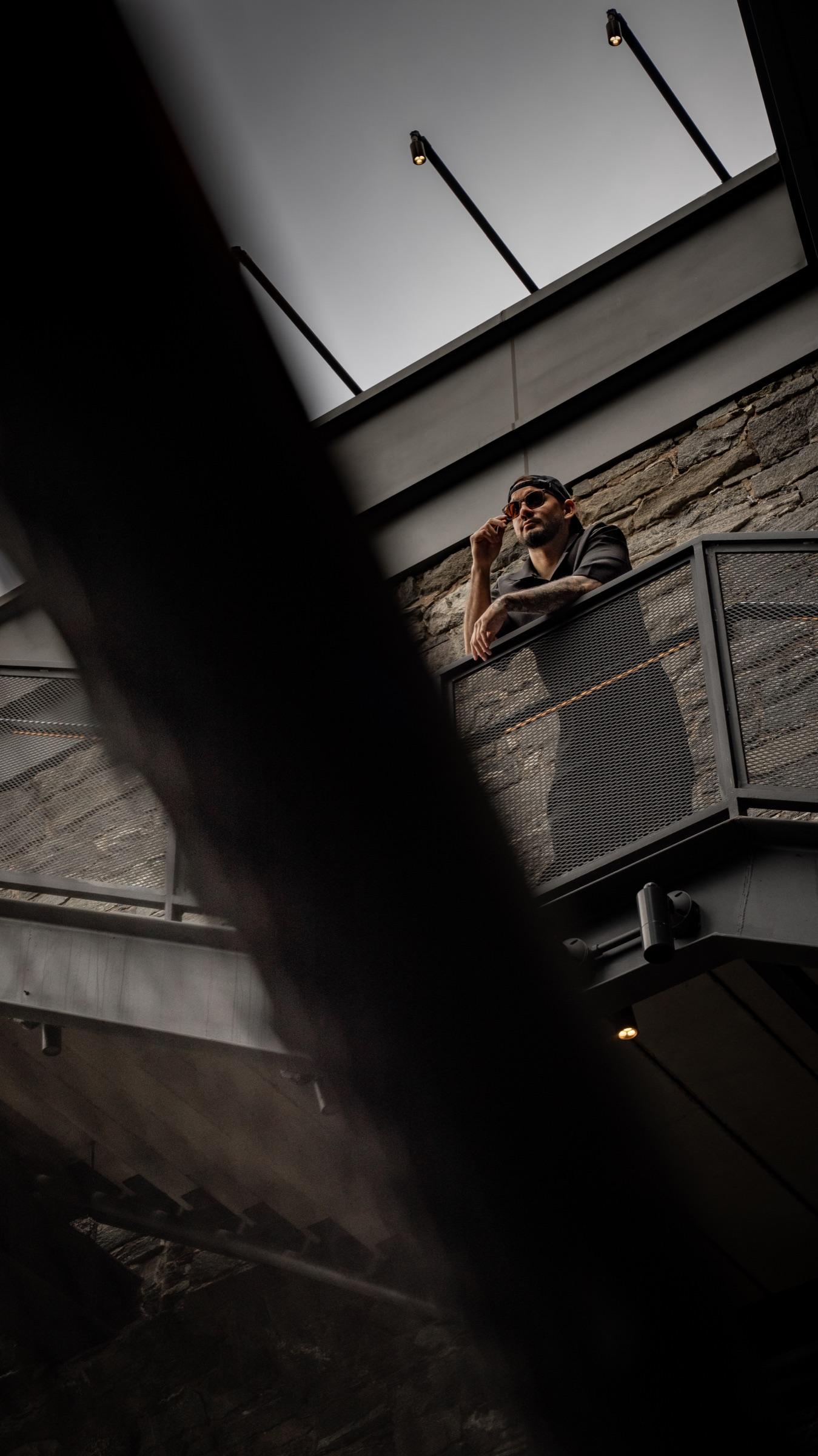Medina leaning on a railing seen from below, dark frame