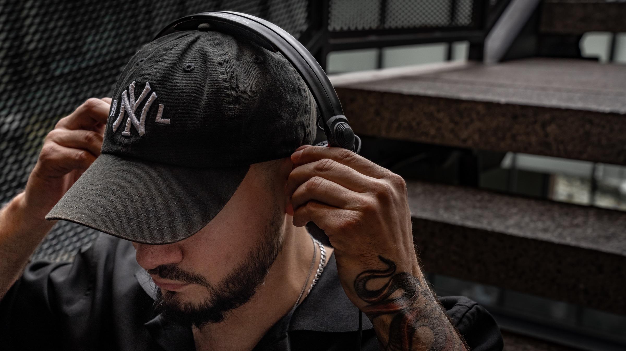 Medina adjusting a black cap and headphones