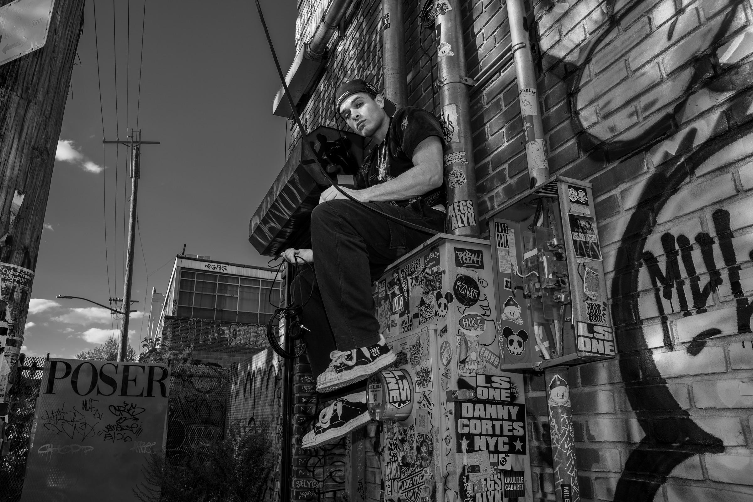 Black-and-white: artist sitting on a graffiti wall