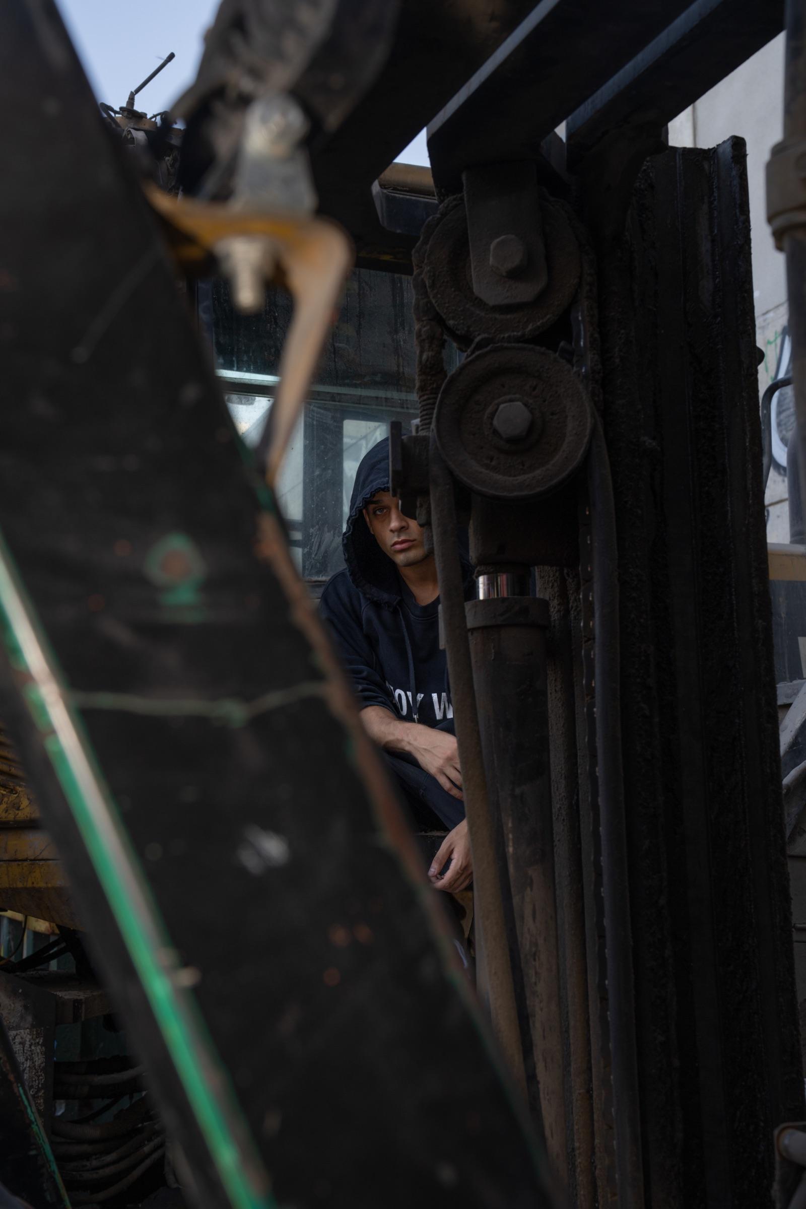 Artist in a hood framed by machinery