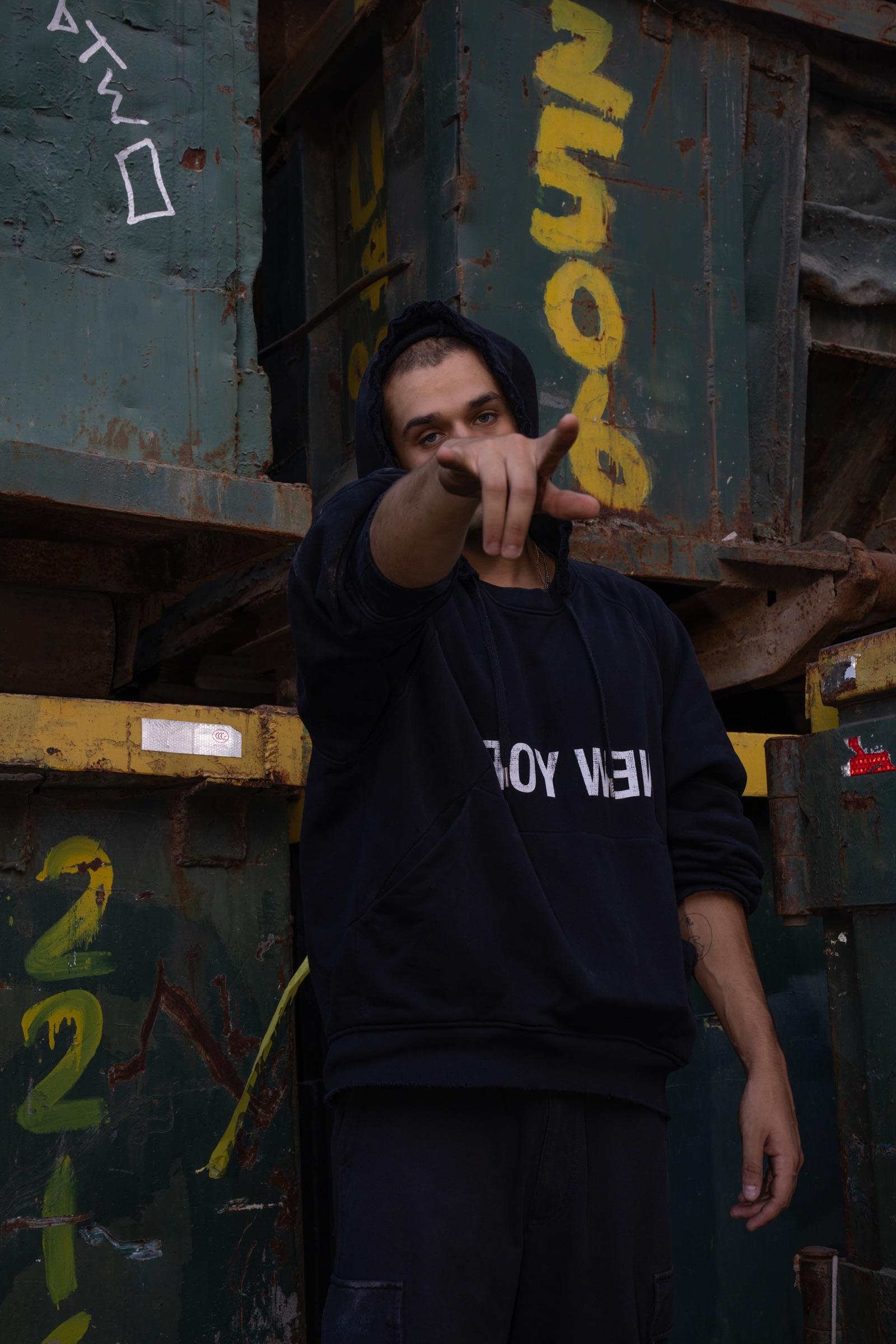 Artist pointing at the camera in front of containers