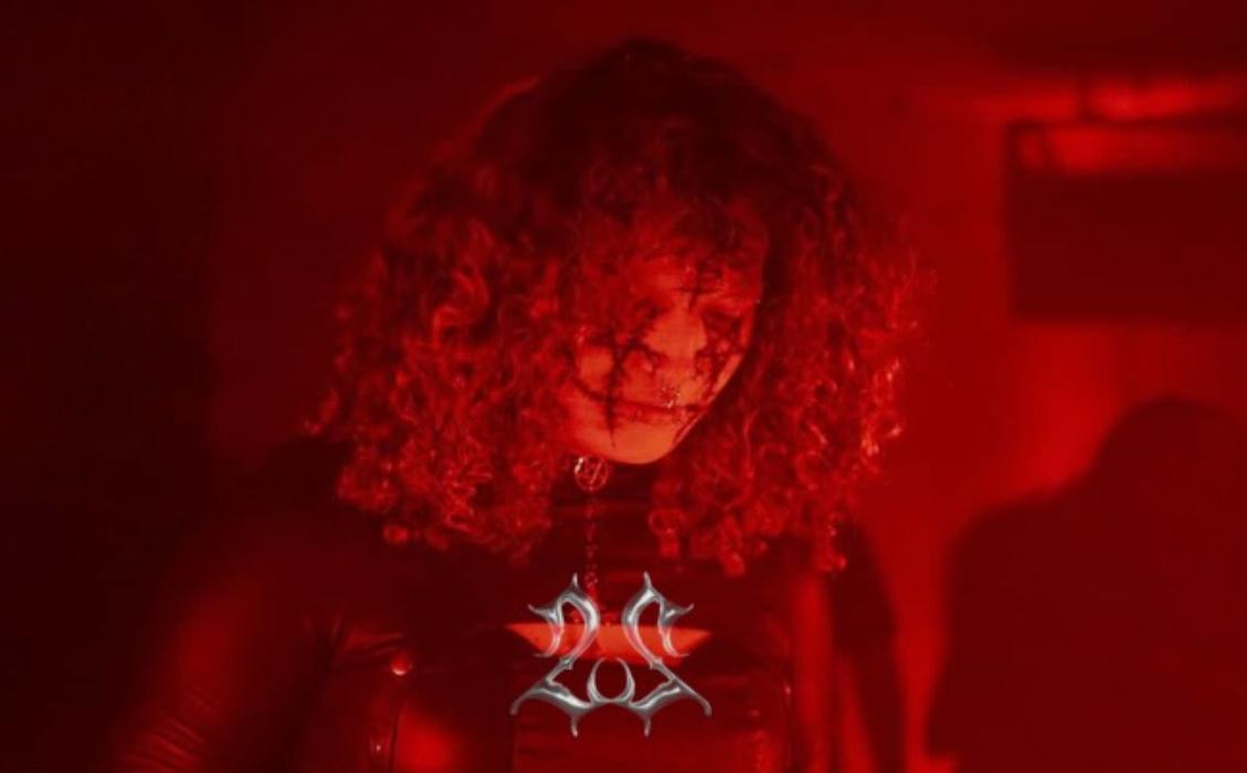 Portrait of Djgothqueen, head bowed, in deep red light