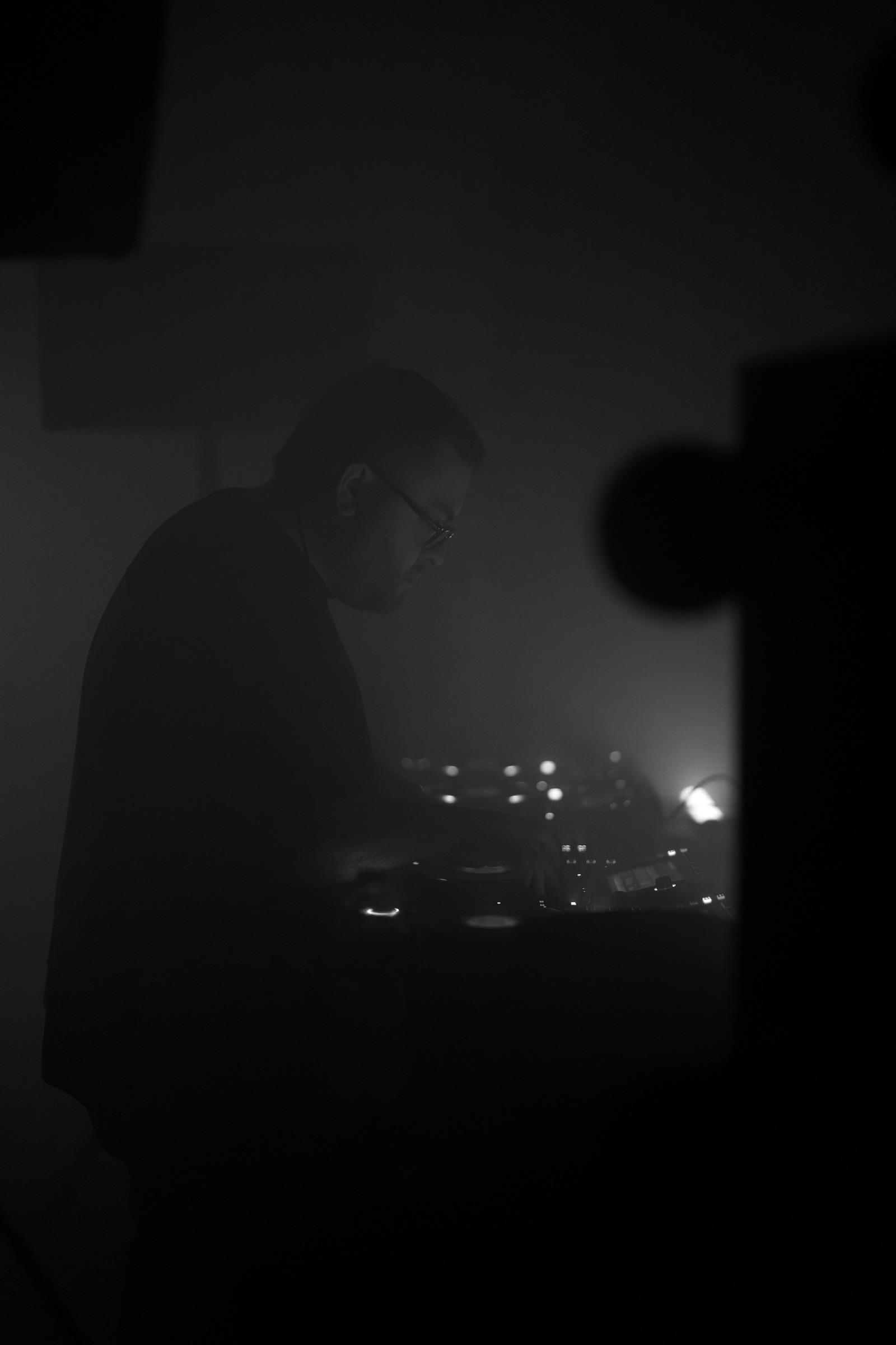 Silhouette of a DJ at the decks in grey haze, vertical frame