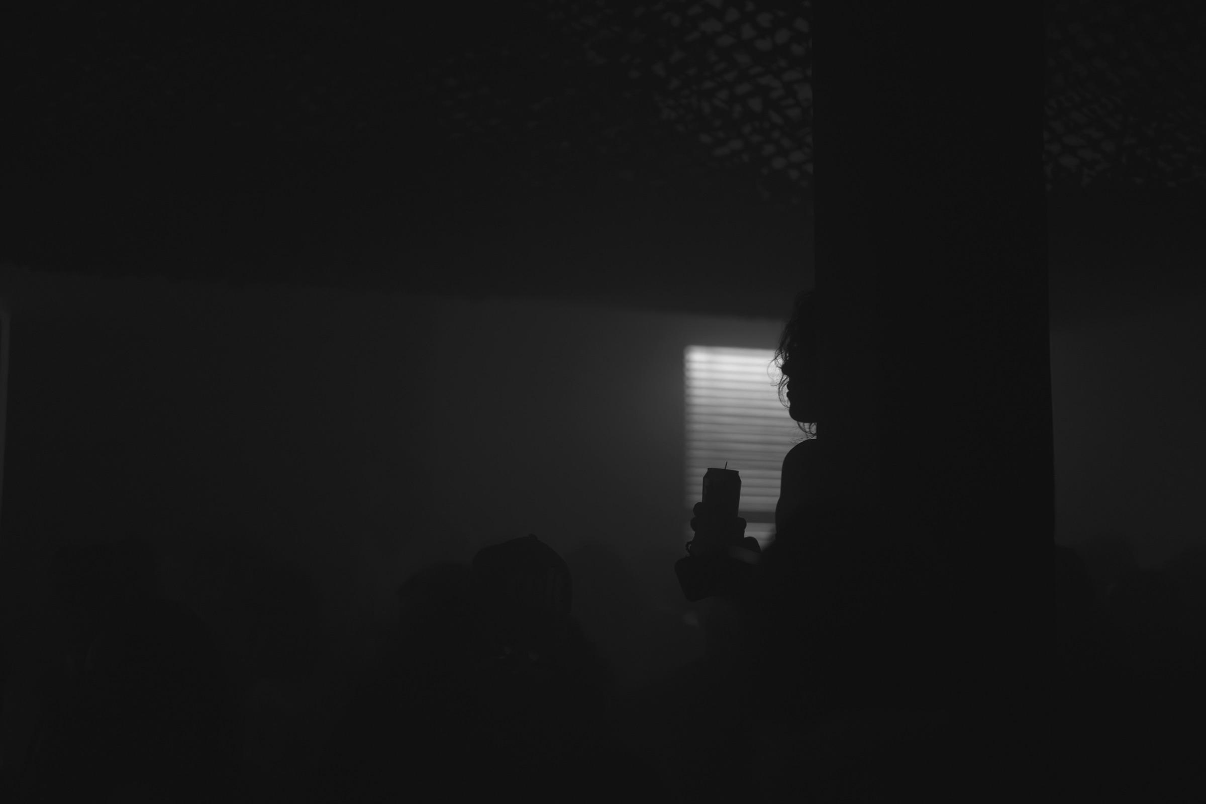Dark room with a lit doorway and a lone silhouette