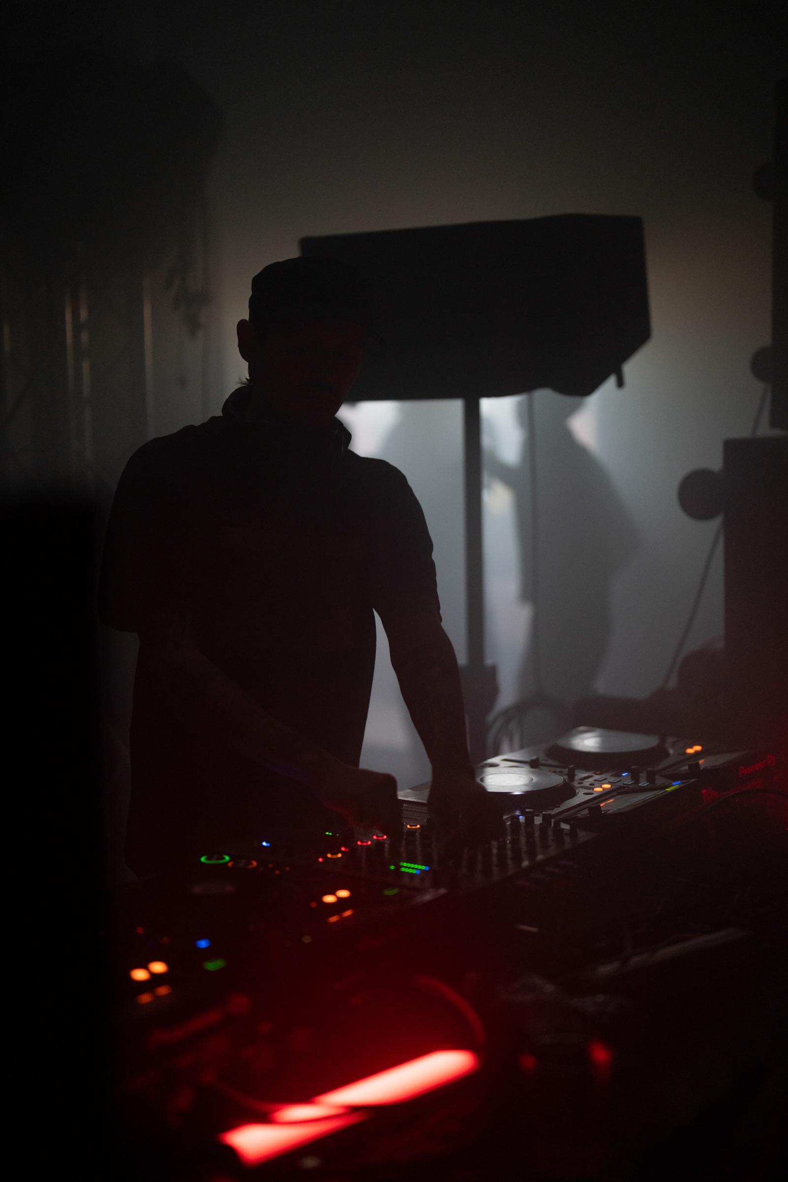 DJ at the decks backlit through fog