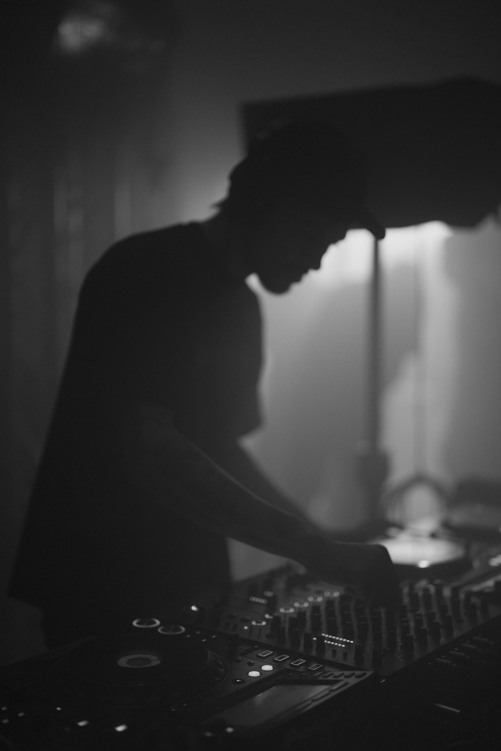 DJ leaning over the mixer, speaker overhead