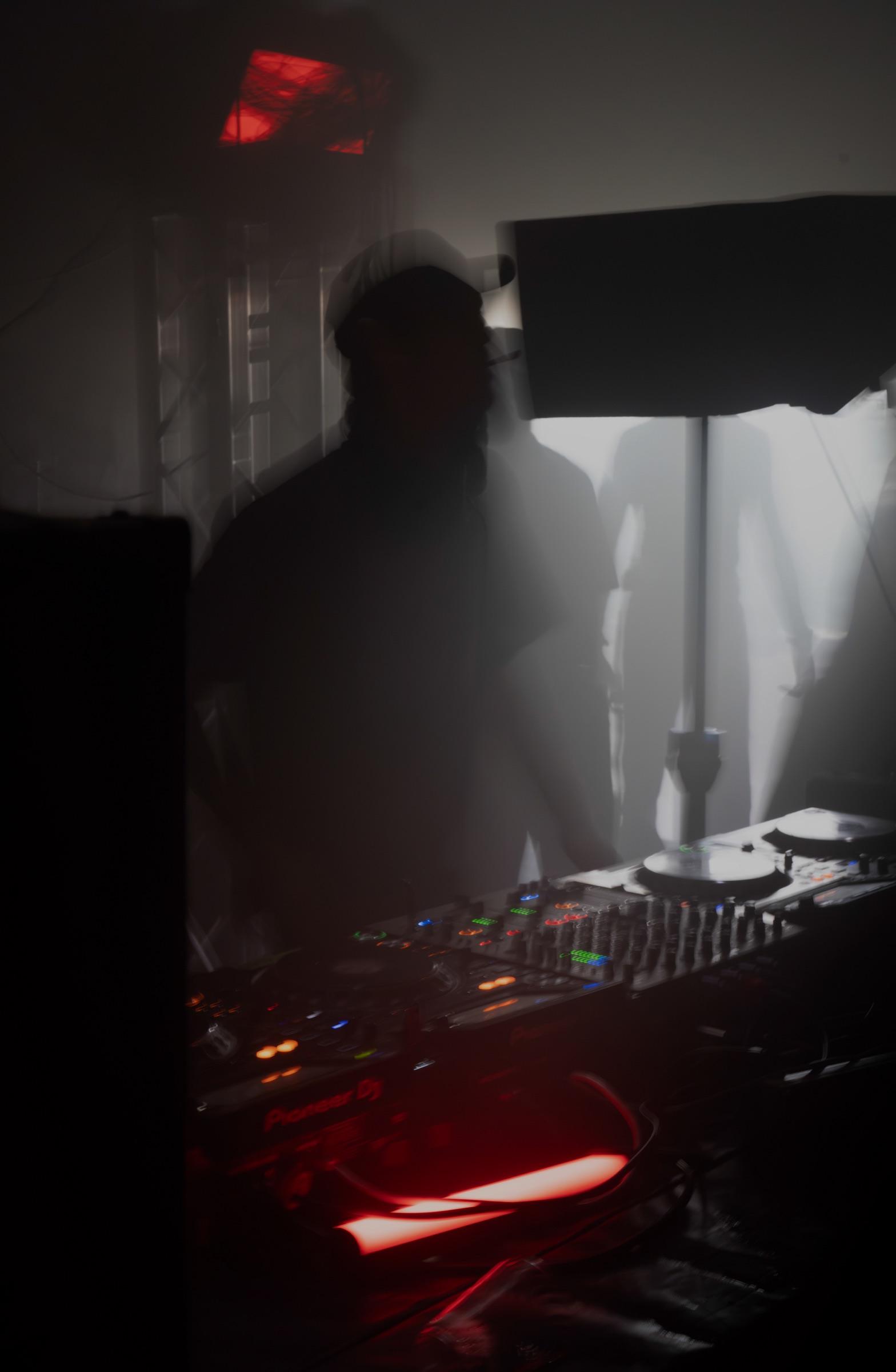 DJ blurred in motion at the decks, red light