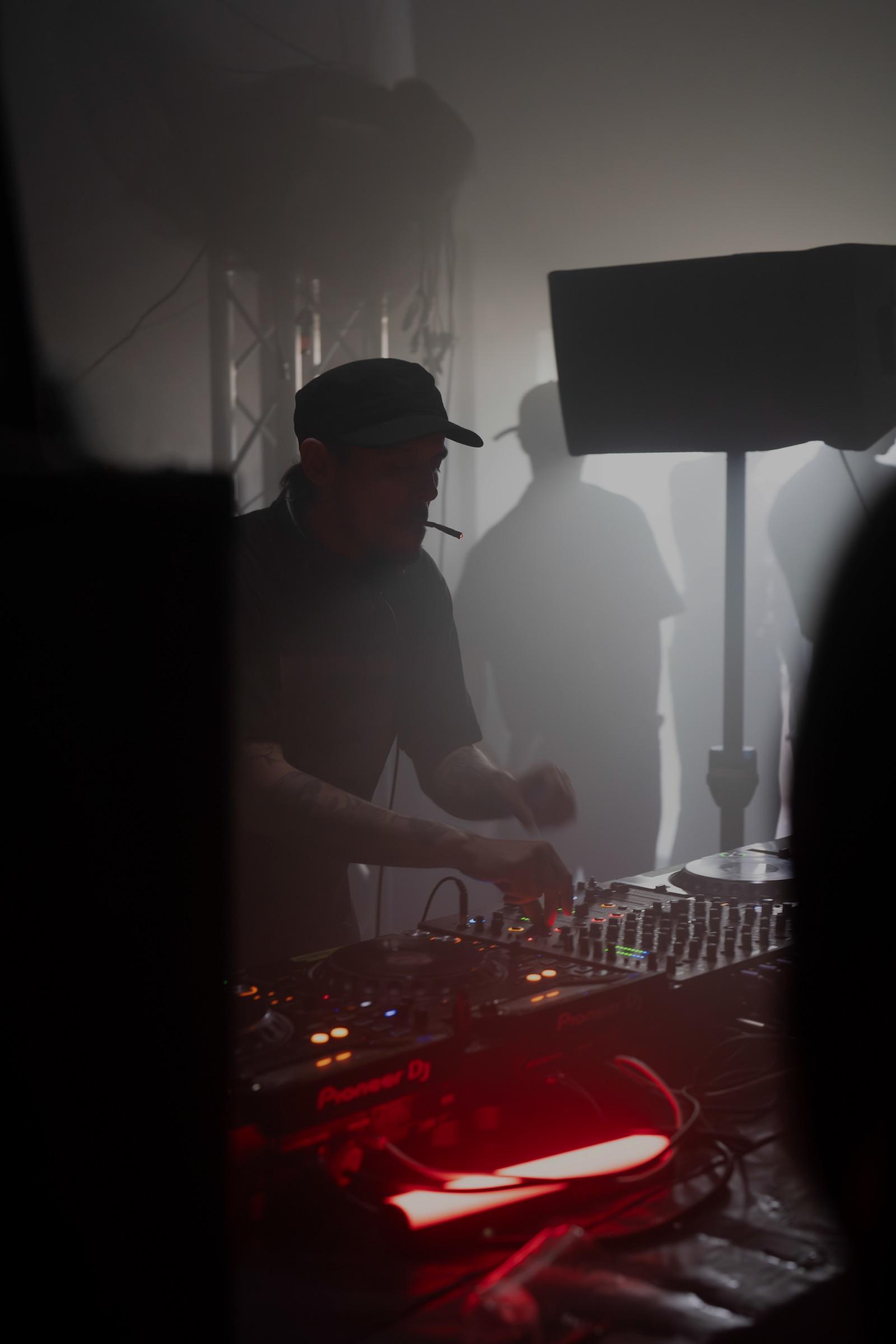 DJ at the decks framed by a dark doorway