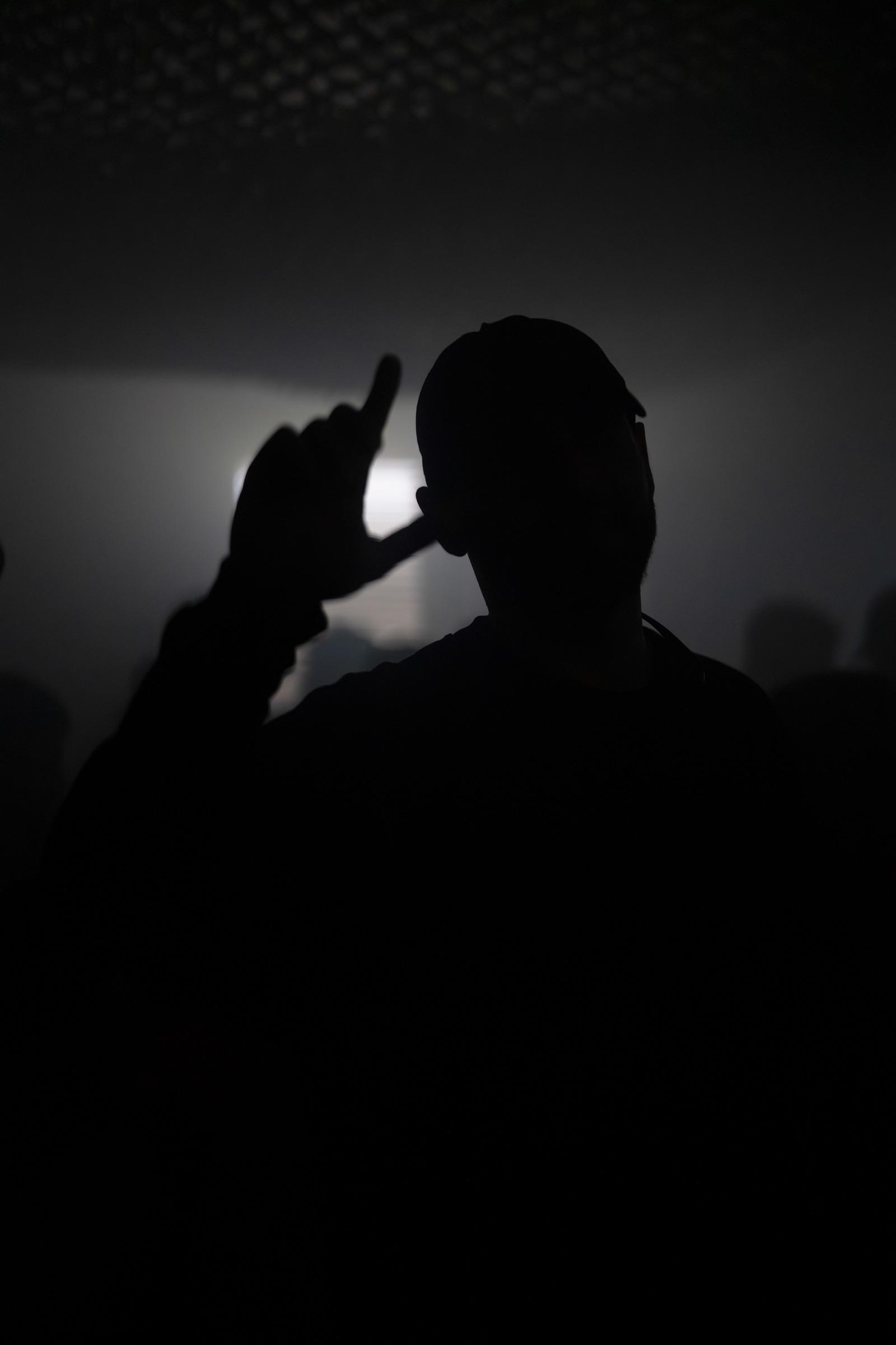 Silhouette in a cap with a hand raised