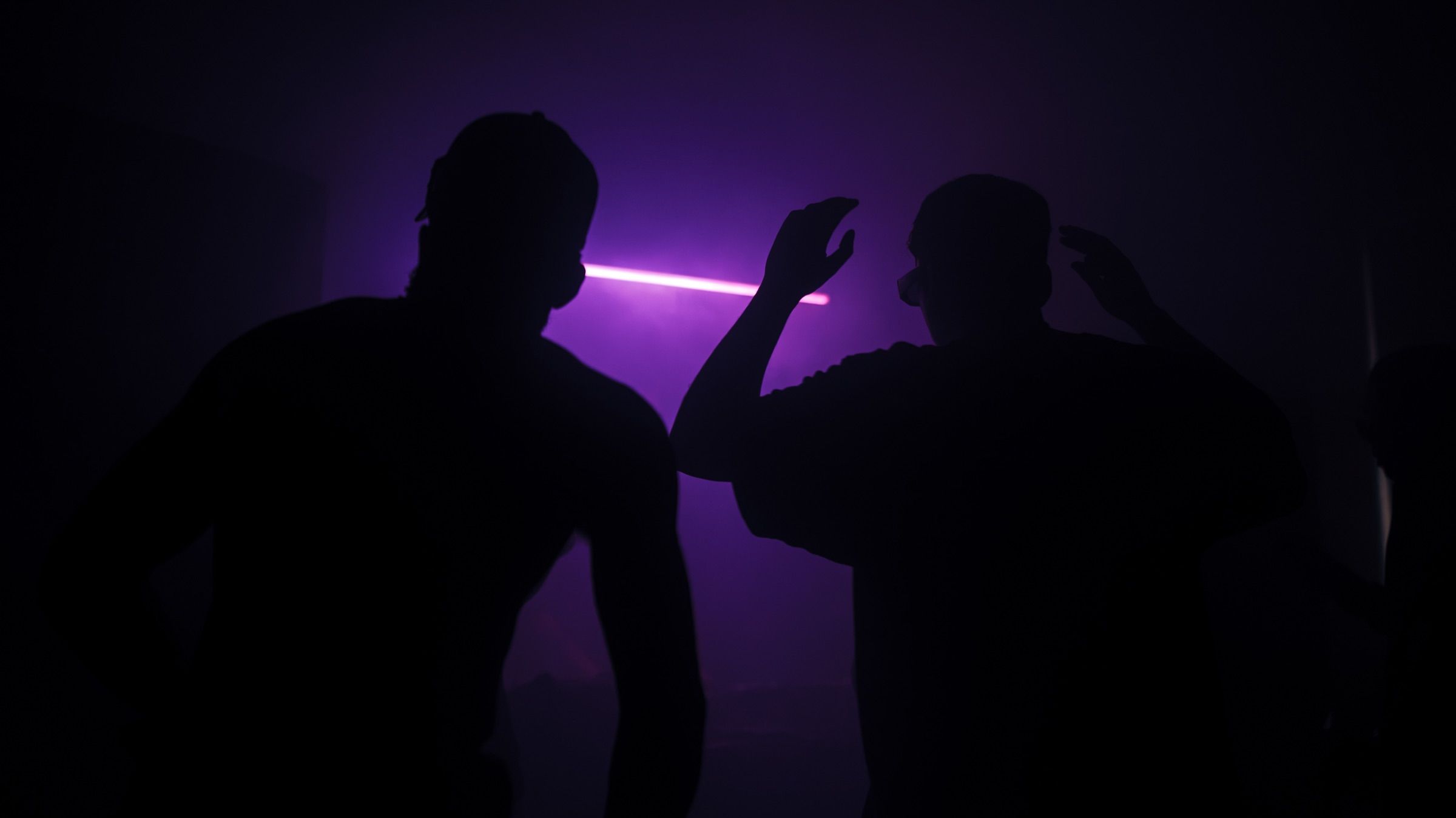Two silhouettes against a purple laser line